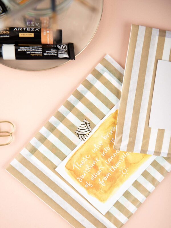 Desk set up with cards packaged in gold stripe bags and thank you notes