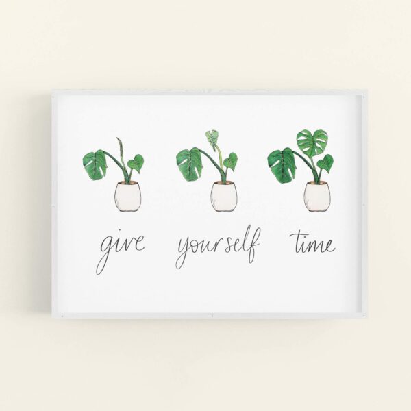 Framed print with hand lettered text 'give yourself time' and illustrations of a slowly uncurling monstera plant