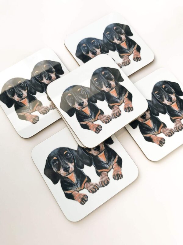 Stack of coasters with illustrated design of 2 cute black and tan sausage dogs