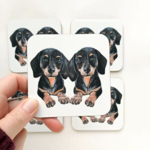 Stack of coasters with illustrated design of 2 cute black and tan sausage dogs