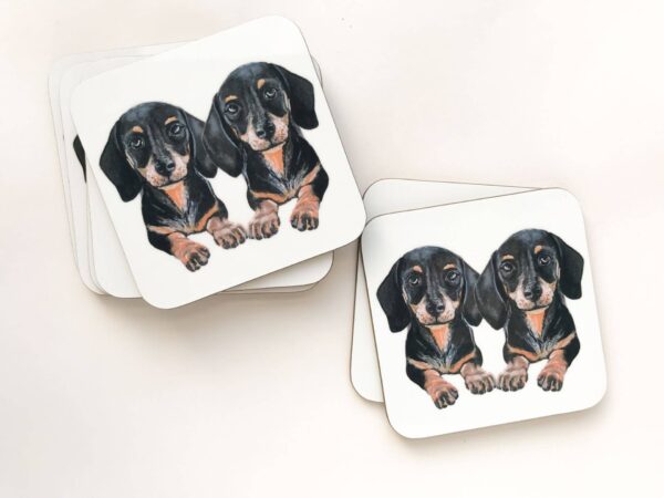 Stack of coasters with illustrated design of 2 cute black and tan sausage dogs