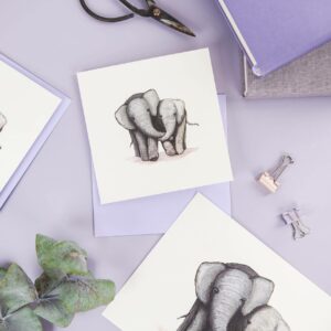 Matching cute elephant illustrated art print and card on a pretty purple desk