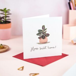 Home sweet home greeting card on a pretty desk, featuring an illustration of a prayer plant