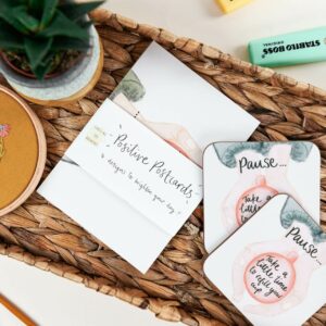 Positive postcard designs on a desk with matching coaster that reads 'Pause... take a little time to refill your cup'