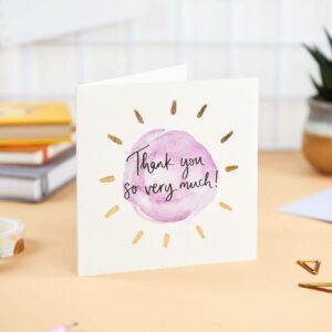 Pretty desk featuring 'thank you so much' card with simple purple design and gold foil detail