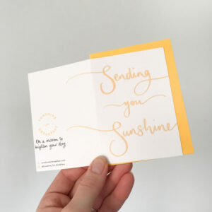 sending you sunshine mini notecard, held displaying the detail of hand lettered text that flows from the front to back of the card