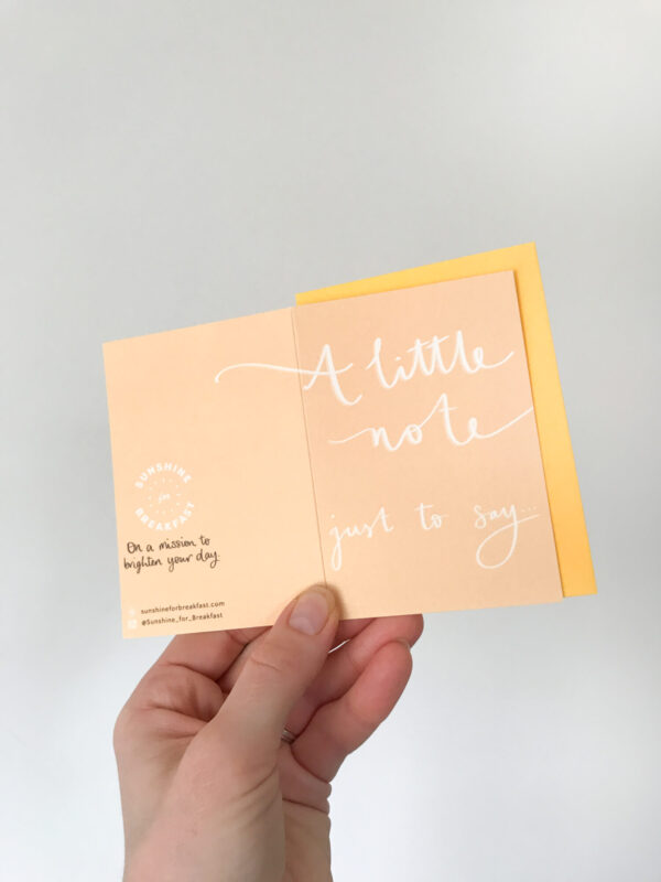 a note to say mini notecard, held displaying the detail of hand lettered text that flows from the front to back of the card