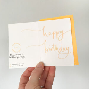 happy birthday mini notecard, held displaying the detail of hand lettered text that flows from the front to back of the card