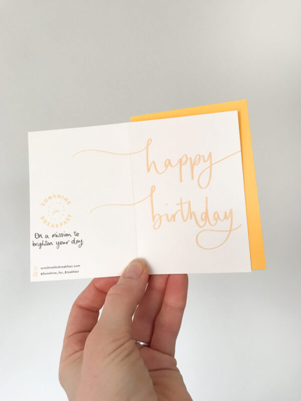 happy birthday mini notecard, held displaying the detail of hand lettered text that flows from the front to back of the card