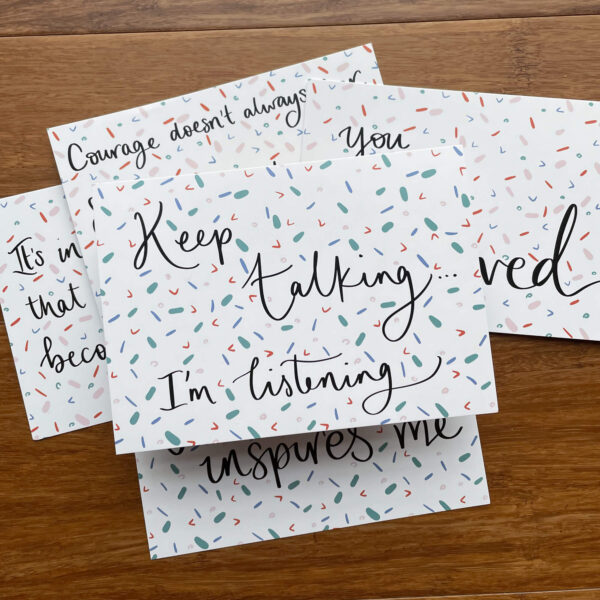 Stack of postcards, the top one reads 'Keep talking, I'm listening'.