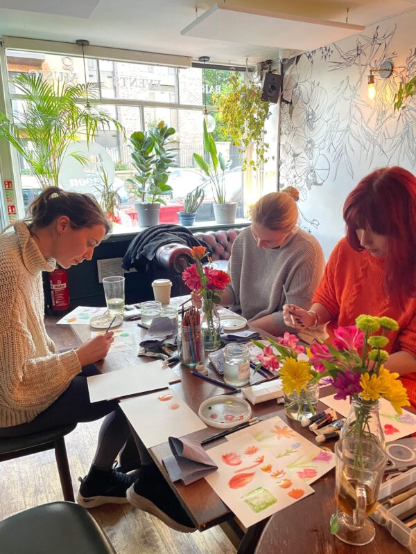 3 women in a watercolour workshop, painting with watercolours.