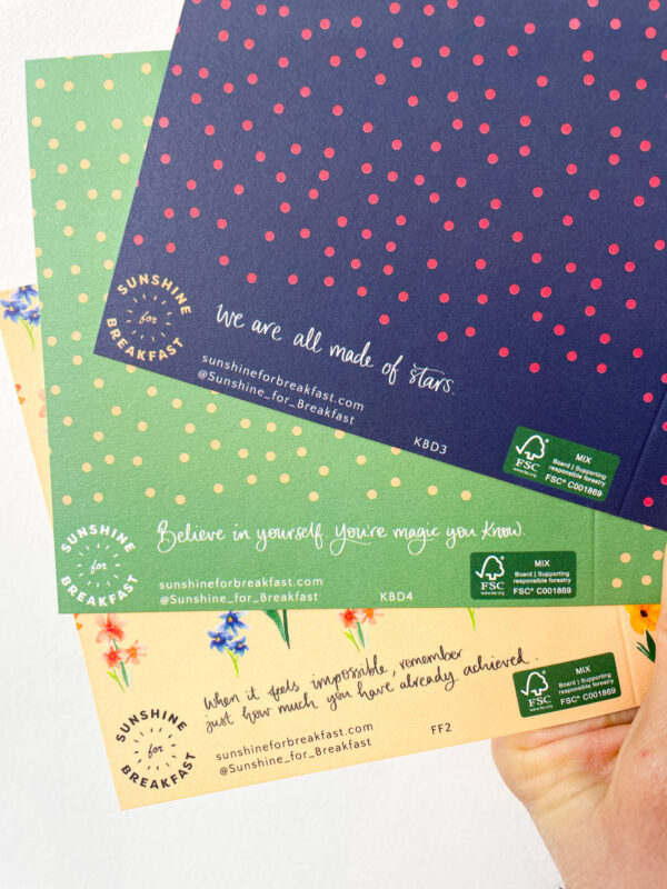 3 cards held up, showing the reverse details. Branding for Sunshine for Breakfast and a different 'sunshine secret' on each card in hand lettered text.