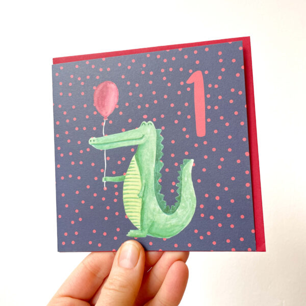 colourful 1st birthday card with a crocodile holding a balloon