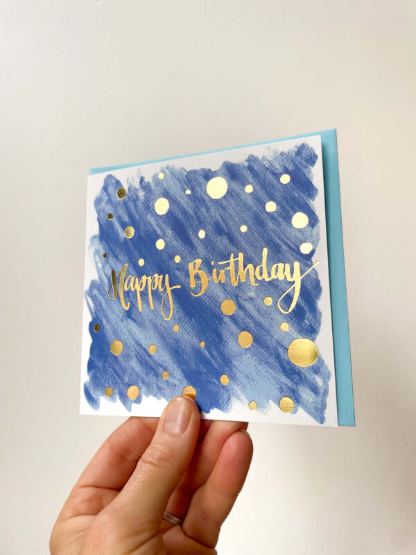 blue birthday card with gold foiling reading 'happy birthday'