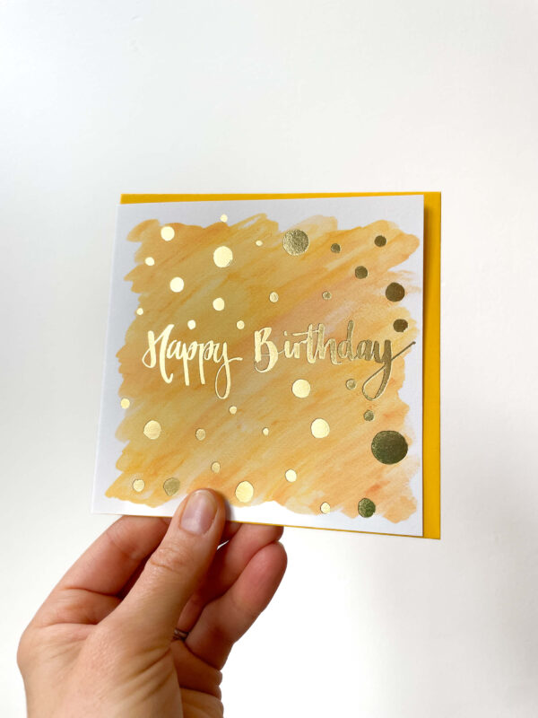 orange birthday card with gold foiling reading 'happy birthday'